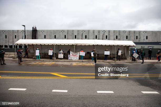 Demonstrators wearing protective masks hold signs during a protest outside an Amazon.com facility in the Staten Island borough of New York, U.S., on...