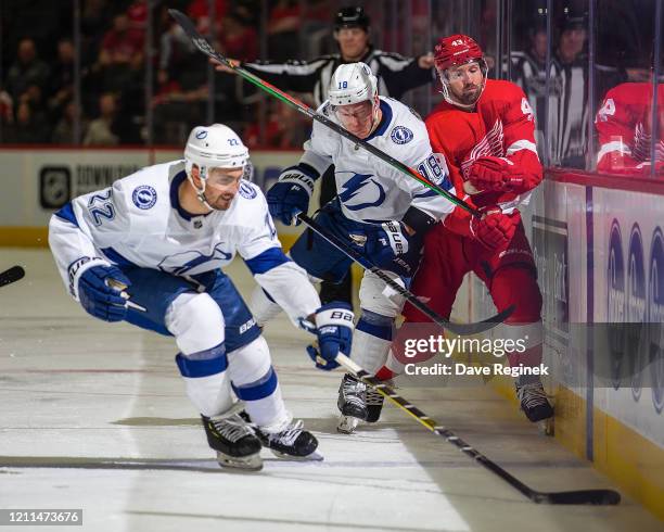 Kevin Shattenkirk of the Tampa Bay Lightning skates after a loose puck as teammate Ondrej Palat body checks Darren Helm of the Detroit Red Wings...