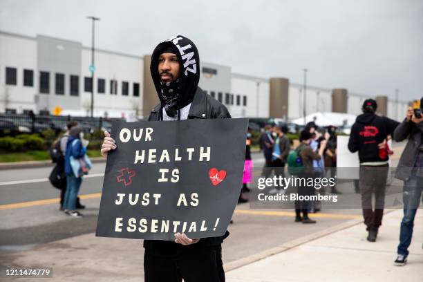 Chris Smalls, a fired Amazon fulfillment center employee, center, holds a sign during a protest outside an Amazon.com facility in the Staten Island...