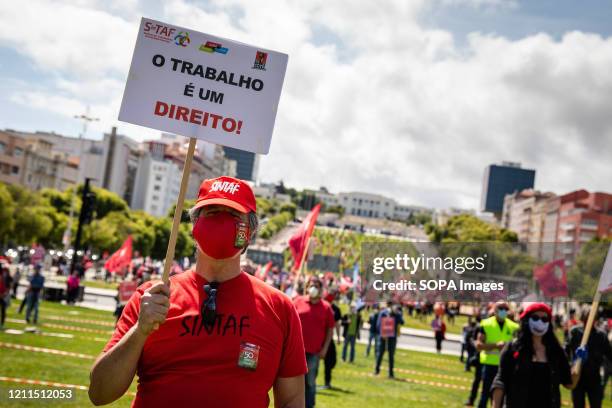 Man wearing a face mask holds a placard during the International Labour day rally. Hundreds gathered Lisbon to celebrate Labour Day organised by the...