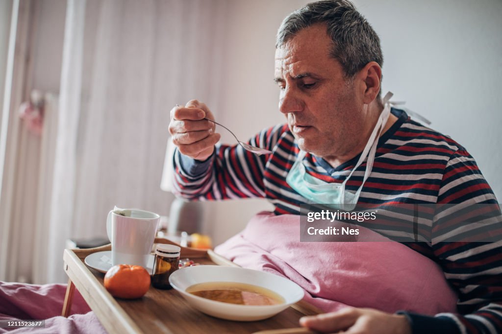 Sick man uses eating soup in bed