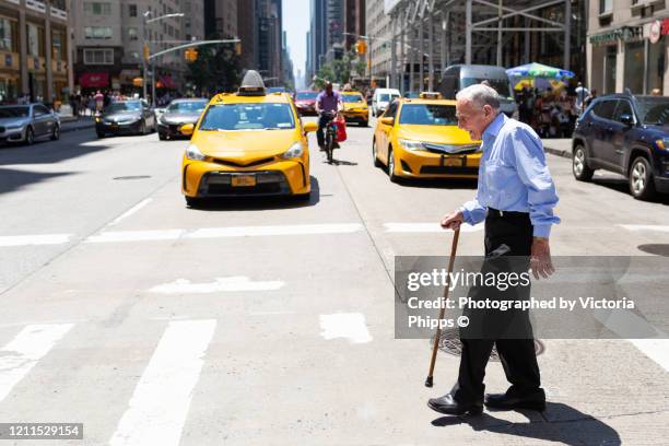 senior man crossing the road in new york city - walking stick stock pictures, royalty-free photos & images