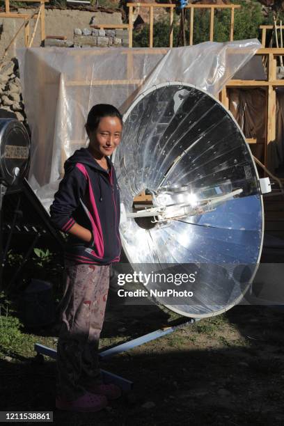 Ladakhi girl uses a parabolic solar cooker to heat water for tea outside her home in the small village of Tangtse, Ladakh, Jammu and Kashmir, India.