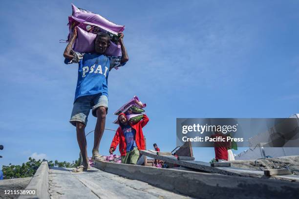 Port laborers carry rice from a truck to be put on traditional wooden boats at the port on World Labor Day. The rice will be brought to a number of...