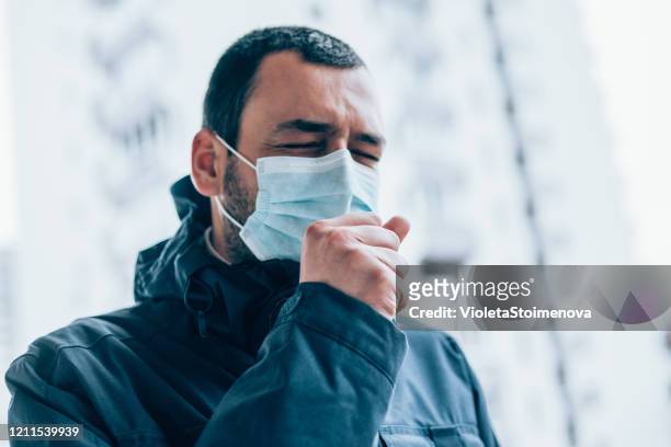 young man wear face mask and coughing outdoors. - protective face mask stock pictures, royalty-free photos & images