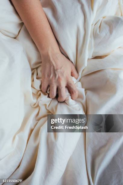 main saisissant une feuille de lit - drap photos et images de collection