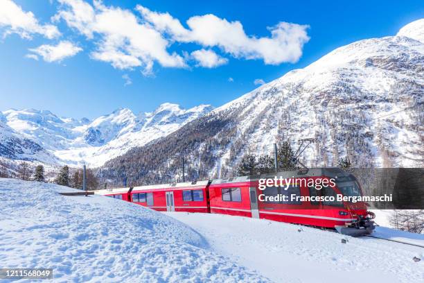 bernina express train in the snowy landscape of bernina pass at day. - swiss culture imagens e fotografias de stock