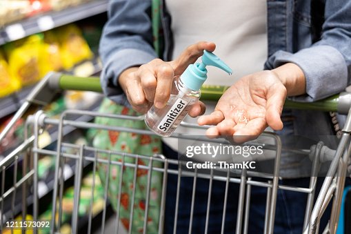Asian shopper disinfecting hands with sanitizer in supermarket during shopping Asian shopper disinfecting hands with sanitizer in supermarket during shopping