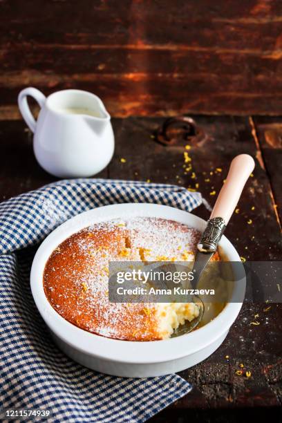 lemon delicious pudding dusted with powdered sugar in a baking bowl on a wooden table, selective focus - souffle stock pictures, royalty-free photos & images