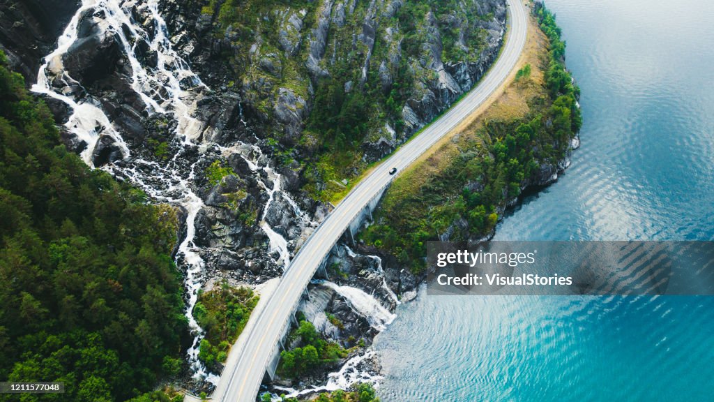 ノルウェーの車、海、滝を備えた風光明媚な山道の空中写真