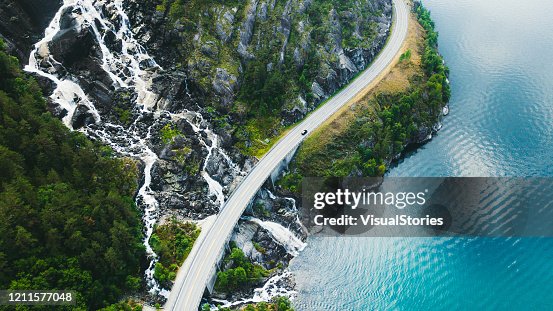 Luchtmening van schilderachtige bergweg met auto, overzees en waterval in Noorwegen Luchtmening van schilderachtige bergweg met auto, overzees en waterval in Noorwegen