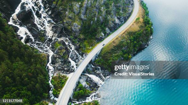 aerial view of scenic mountain road with car, sea and waterfall in norway - nordic nature stock pictures, royalty-free photos & images