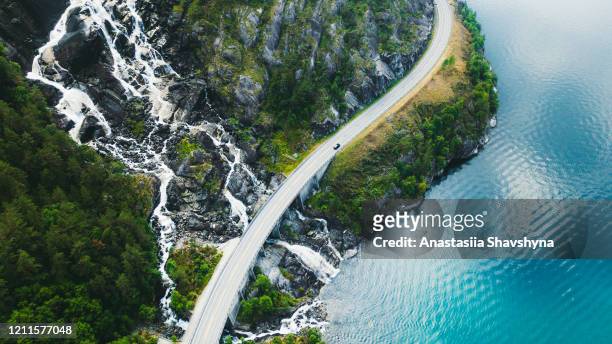 aerial view of scenic mountain road with car, sea and waterfall in norway - green road imagens e fotografias de stock