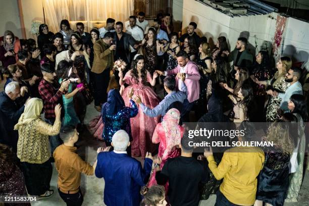 Syrian Kurdish couple Dilxwaz Ali and Arishan Ali dance with relatives during their engagement ceremony at home in the city of Qamishli in Syria's...