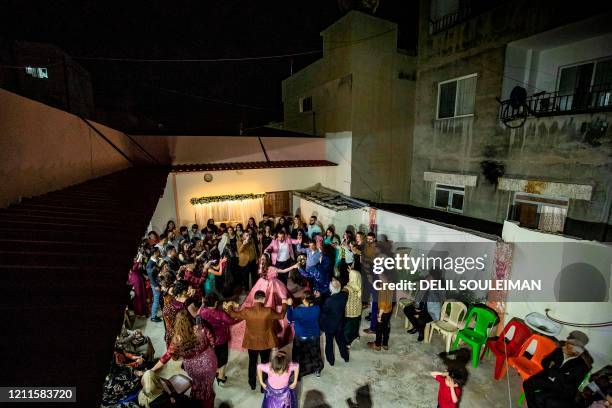 Syrian Kurdish couple Dilxwaz Ali and Arishan Ali dance with relatives during their engagement ceremony at home in the city of Qamishli in Syria's...