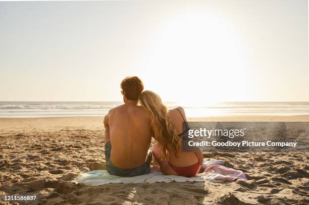 junges paar in bademode mit blick auf den ozean am späten nachmittag - beach couple stock-fotos und bilder