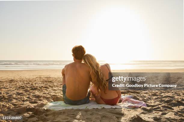 young couple in swimwear looking at the ocean in the late afternoon - couple and beach imagens e fotografias de stock