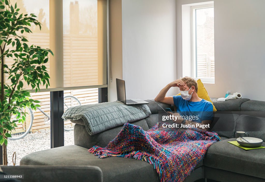 Man in self isolation on the sofa with the flu