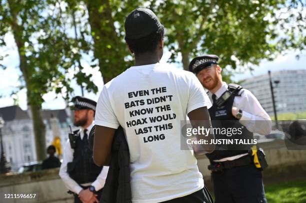 One of a small group of anti-lockdown protesters speaks to a police officer as they gather outside New Scotland Yard in Victoria, London on May 2...