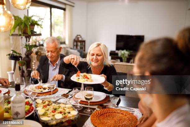 mujer mayor sirviendo comida para la familia - easter family fotografías e imágenes de stock