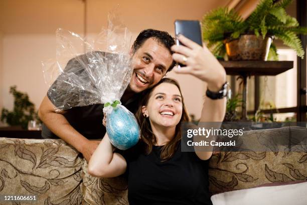 couple taking a selfie with chocolate easter egg - sharing chocolate stock pictures, royalty-free photos & images