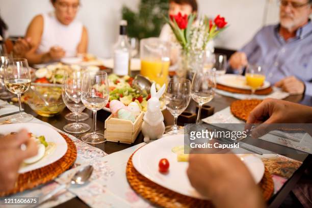 famille mangeant ensemble sur la table pour pâques - famille pâques photos et images de collection