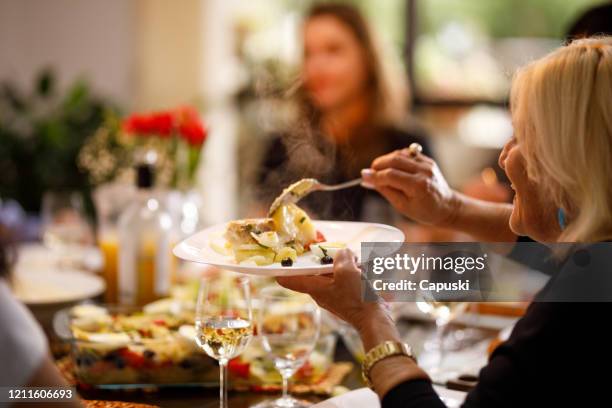 senior woman serving fresh hot food on easter - cod dinner stock pictures, royalty-free photos & images