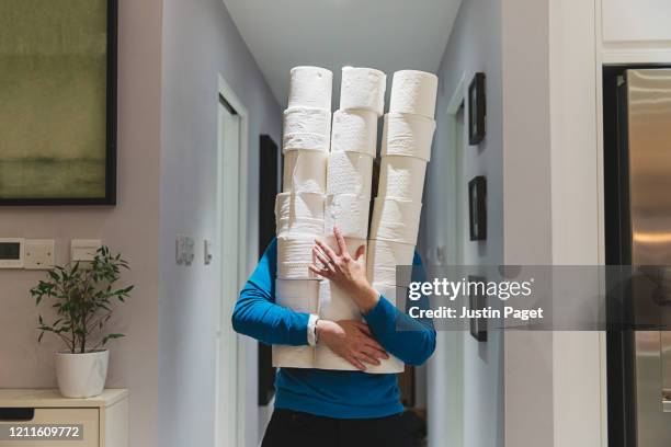 person holding large piles of toilet rolls - coronavirus social distancing stock pictures, royalty-free photos & images