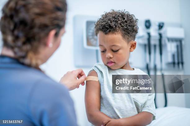 doctor putting bandage on little boy stock photo - child vaccination stock pictures, royalty-free photos & images