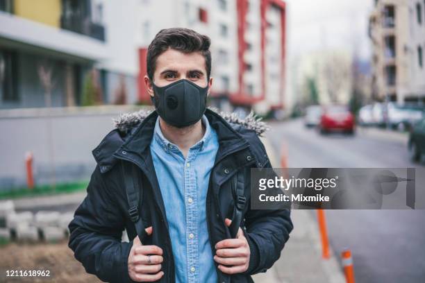 young man wearing real pollution mask for protection in the city - air respirator mask stock pictures, royalty-free photos & images