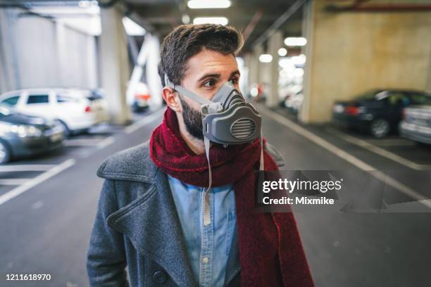 young man wearing respirator mask for protecting from smoggy air in the big city - air respirator mask stock pictures, royalty-free photos & images