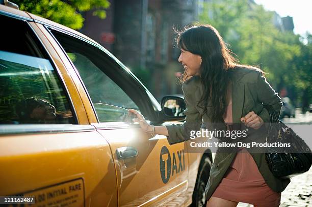 young adult woman talking to taxi drive - taxi amarillo fotografías e imágenes de stock