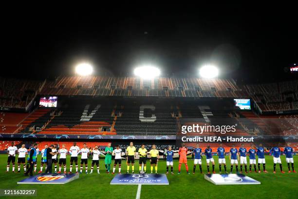 In this handout image provided by UEFA, Both teams line up in an empty stadium ahead of the UEFA Champions League round of 16 second leg match...