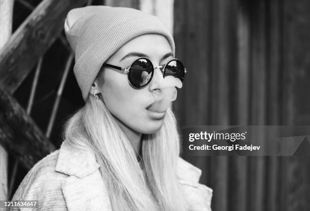 sexy hipster woman in sunglasses and hat, blowing smoke from a sigarette. swag, hippie style girl. old window on background. - luxury lounges stock pictures, royalty-free photos & images