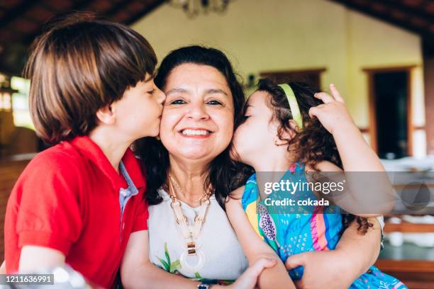 kleinkinderen die grootmoeder op haar wangen kussen - friends kissing cheeks stockfoto's en -beelden