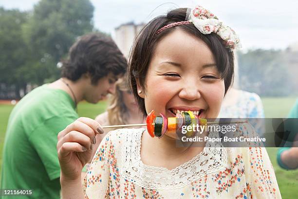 a smiling happy girl in the park eating - asian person bbq stock-fotos und bilder