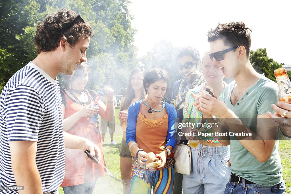 Group of friends huddled around a bbq grill