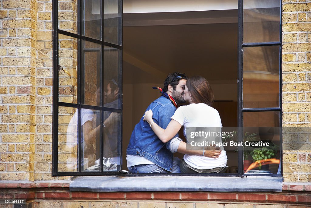 Couple kissing by the window sill