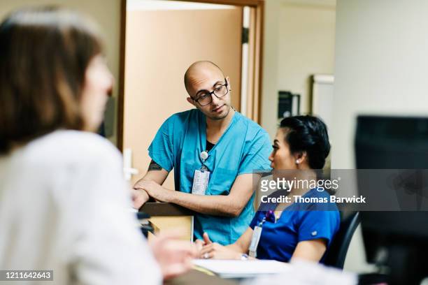 medical staff in discussion at nurses station in hospital - schwesterntisch stock-fotos und bilder