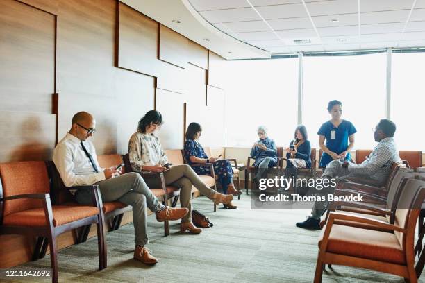 nurse greeting patient in medical office waiting room - waiting room stock pictures, royalty-free photos & images