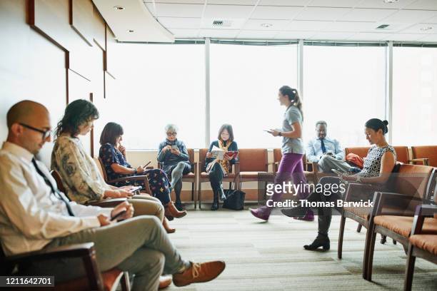 nurse walking through medical office waiting room to greet patient - examining room stock pictures, royalty-free photos & images
