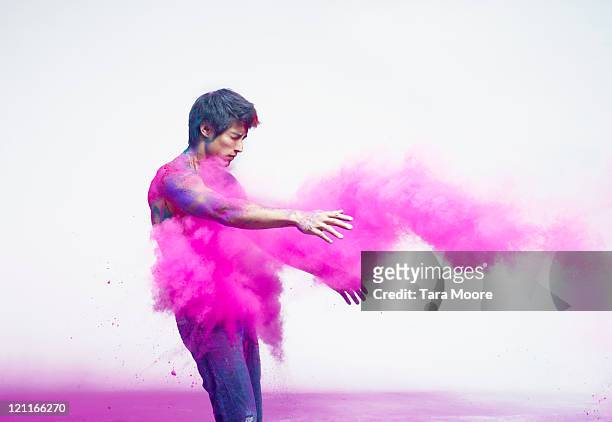 man being impacted by bright pink powder paint - powder throw fotografías e imágenes de stock