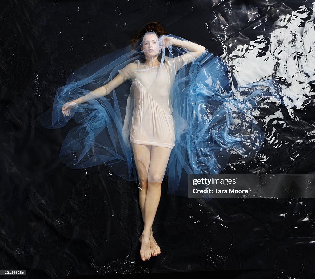 Woman floating in water covered in blue material