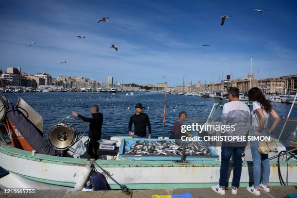 Couple looks at fishermen selling fishes from their boat on the Vieux Port harbour of Marseille, southern France, on May 3 amid the spread of the...