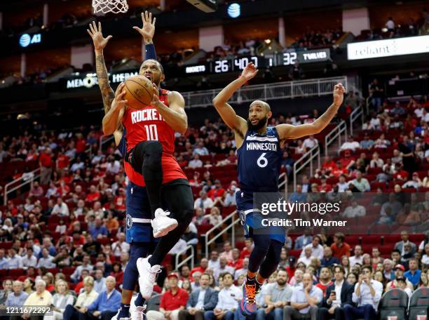 Eric Gordon of the Houston Rockets drives to the basket while defended by D'Angelo Russell of the Minnesota Timberwolves and Jordan McLaughlin in the...