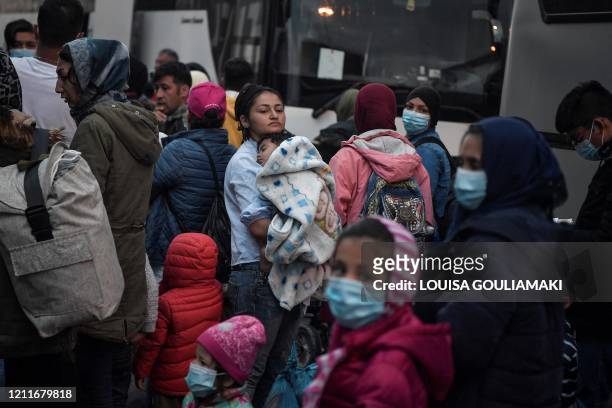 Woman holds her child as migrants transferred from the Moria camp on the island of Lesbos disembark in the port of Piraeus near Athens early on May...