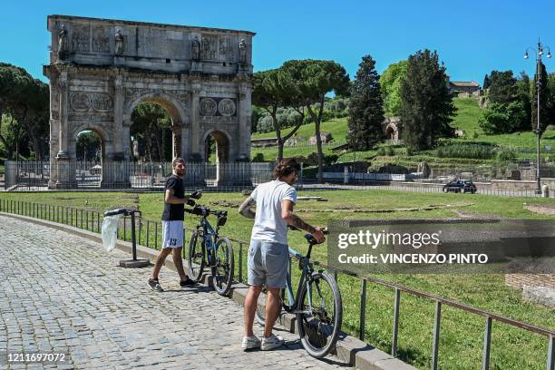 Men park their bicycle near the Arch of Constantine monument in central Rome on May 4, 2020 as Italy starts to ease its lockdown, during the...