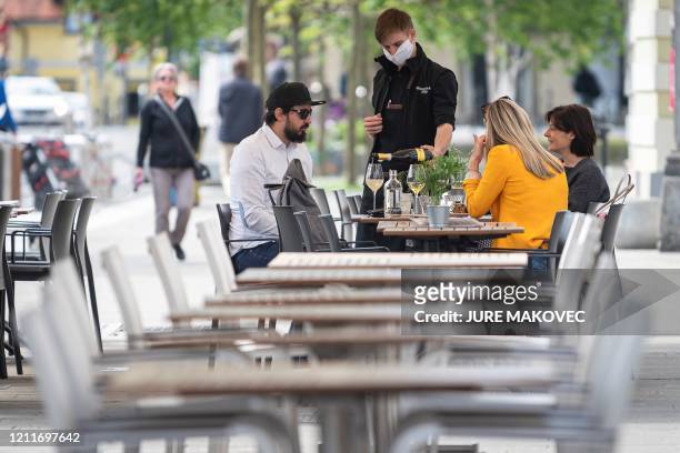 Bartender wearing a mask serves wine to clients at a caffe terrace in Ljubljana, on May 4 on the first day of the lockdown ease amid the Covid-19...