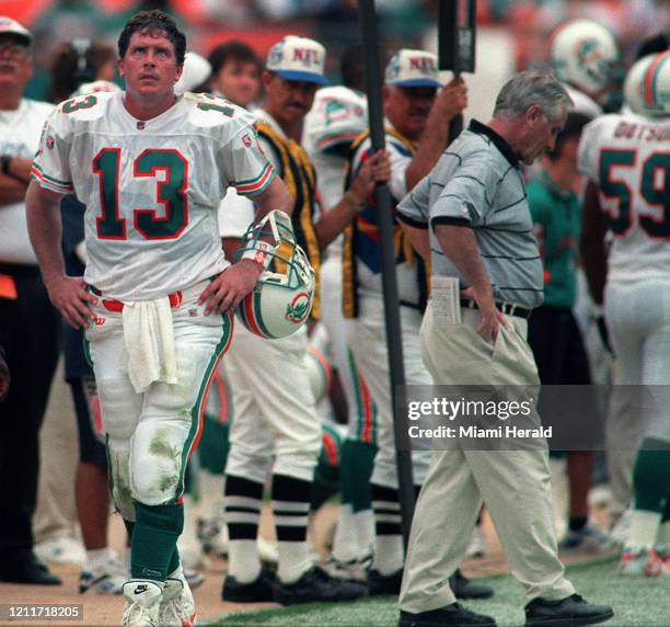 Miami Dolphins quarterback Dan Marino walks on the sidelines looking at the scoreboard as coach Don Shula drops his head after Marino threw an...