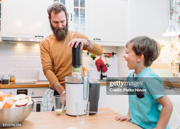 papa macht frischen gesunden saft für seinen kleinen sohn - küche überrascht mann stock-fotos und bilder